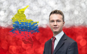 mężczyzna w garniturze w tle flaga polski i kolumbii