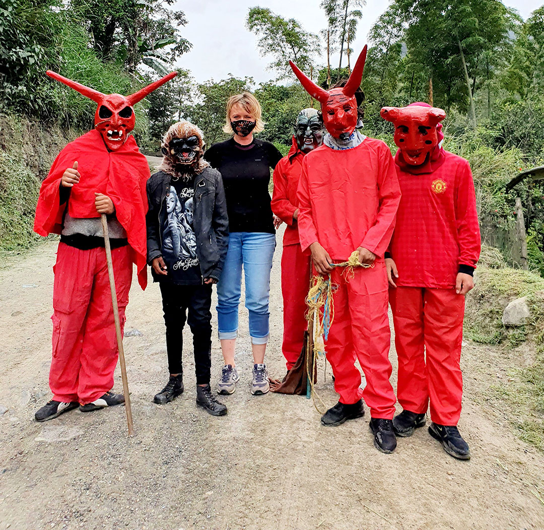 Przebierańcy w czwrwonych kostiumach diabłów i kobieta 